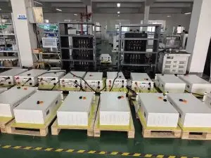 ** Weltrus C&I ESS factory floor showing battery modules on pallets, aging racks, and test monitors
