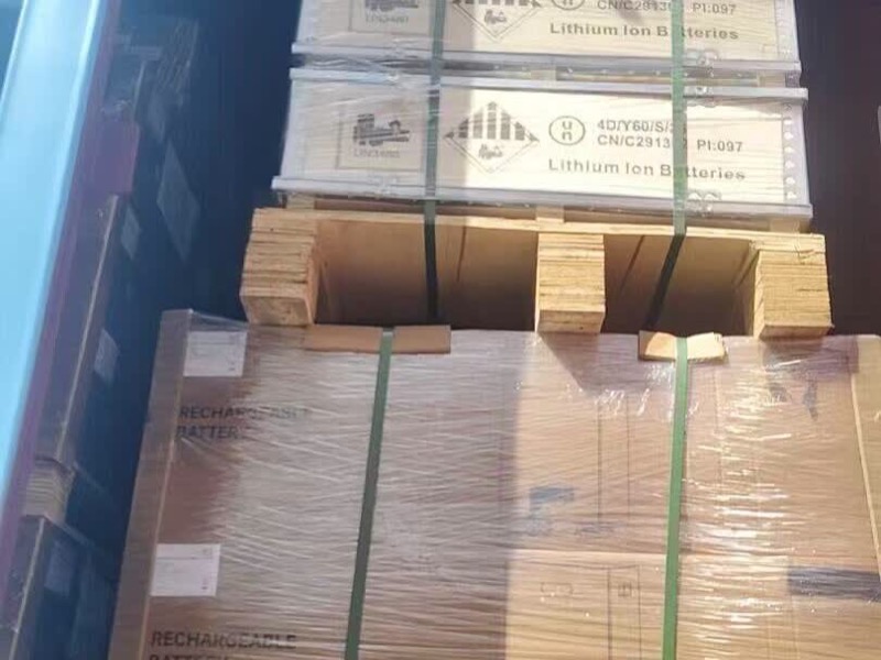 Wooden lithium-ion battery crates stacked above rechargeable-battery cartons with transport marks