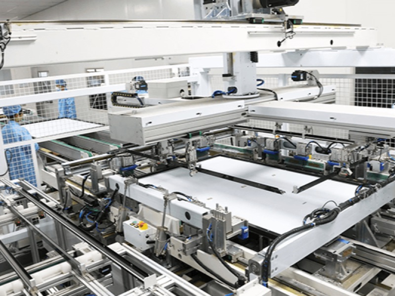 Gantry and fixtures over a solar module lay-up station with an operator in a clean gown