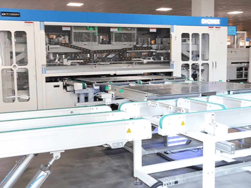 Enclosed stringer-class machine feeding solar module conveyors on the factory floor